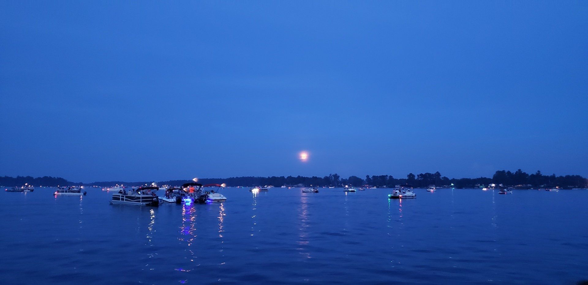 A group of boats are floating on a lake at night.