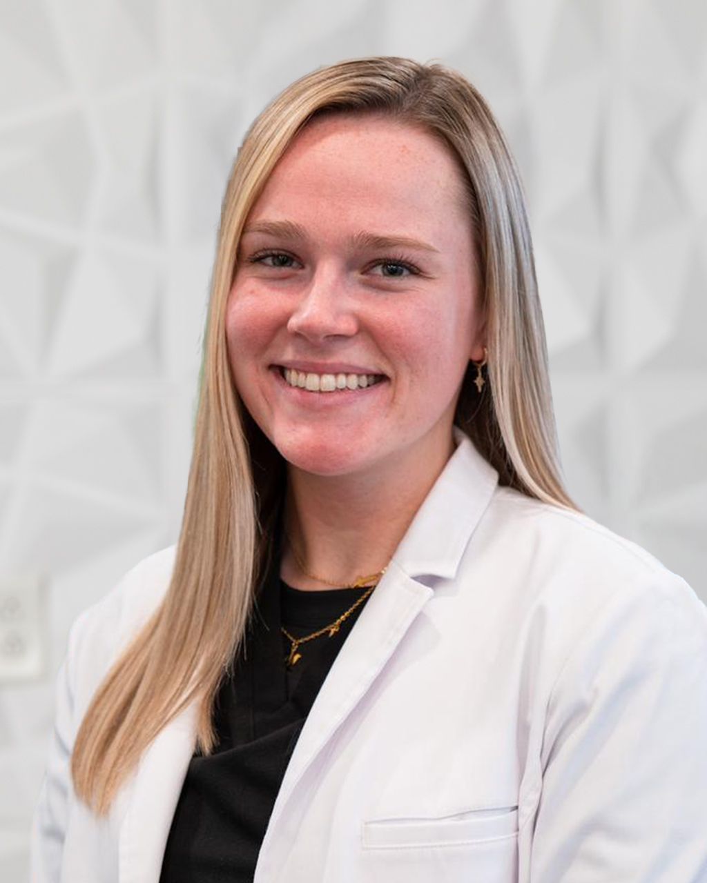 Woman in white lab coat smiles.