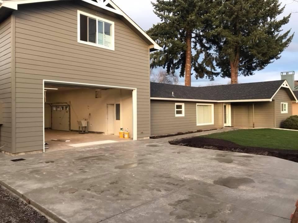Modern bathroom with a glass shower, wall-mounted toilet, vanity, and large mirror; beige walls, brown cabinet, and white sink.