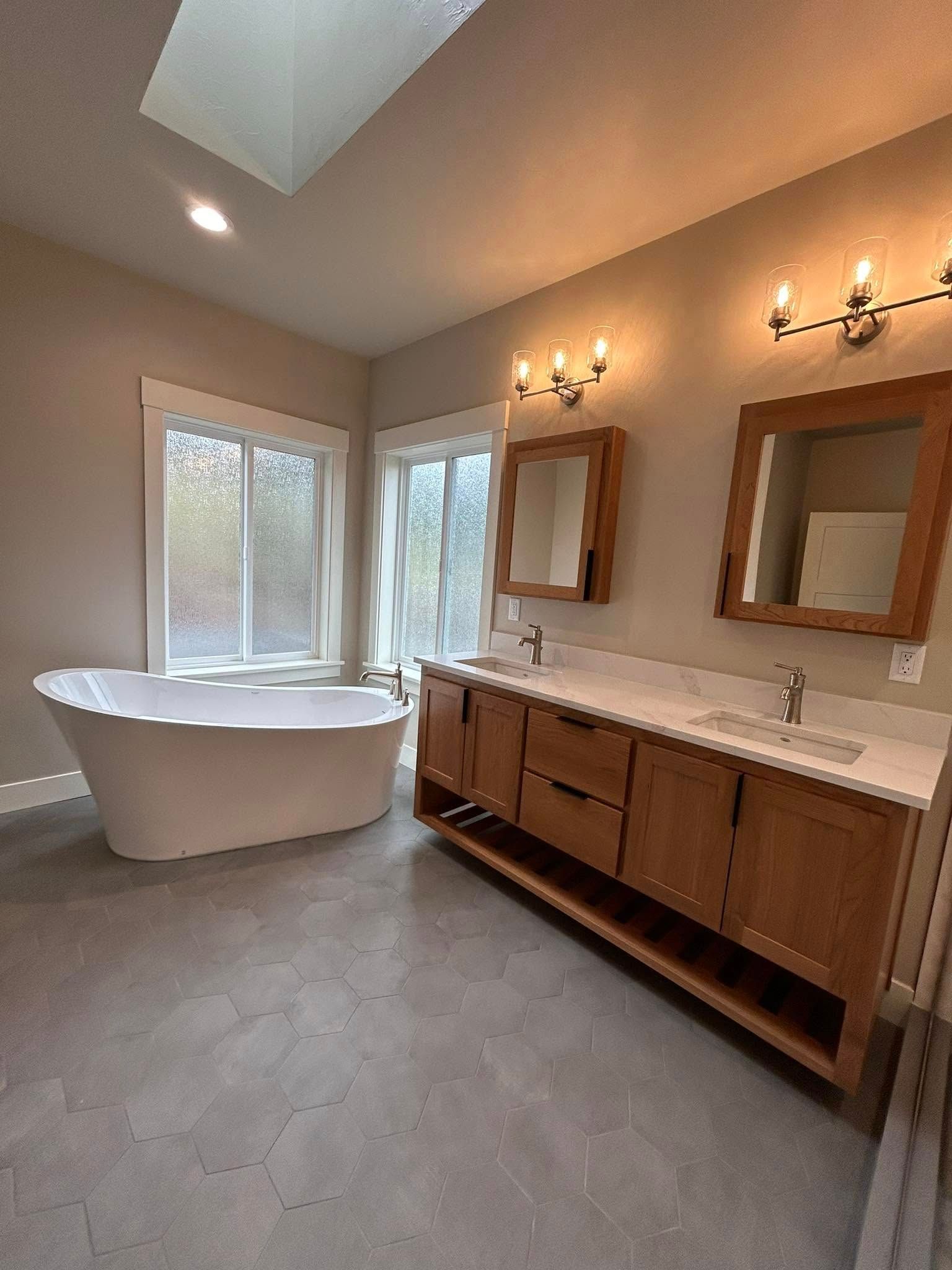 Bathroom with two white vessel sinks on a granite countertop, light wood cabinets, and a door to the left.