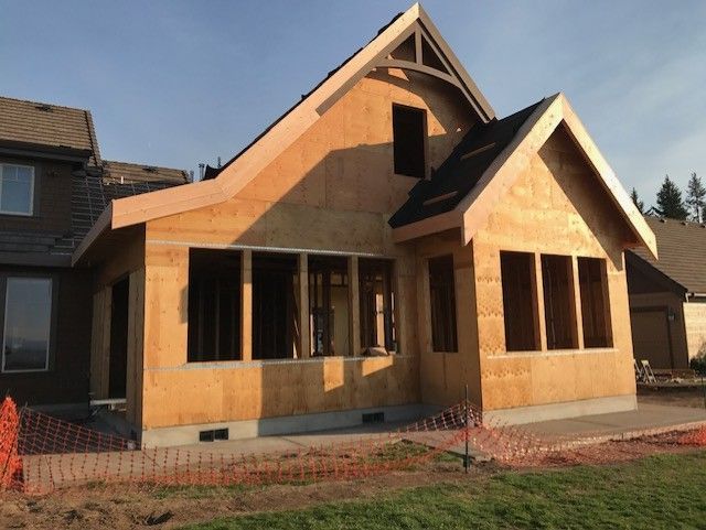 Interior view of an unfinished room with a large, multi-pane window offering a view of the outdoors. Sunlight streams in.