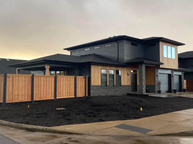 Construction of a two-story house with exposed framing and concrete block walls. Lumber and building materials are scattered in the foreground.