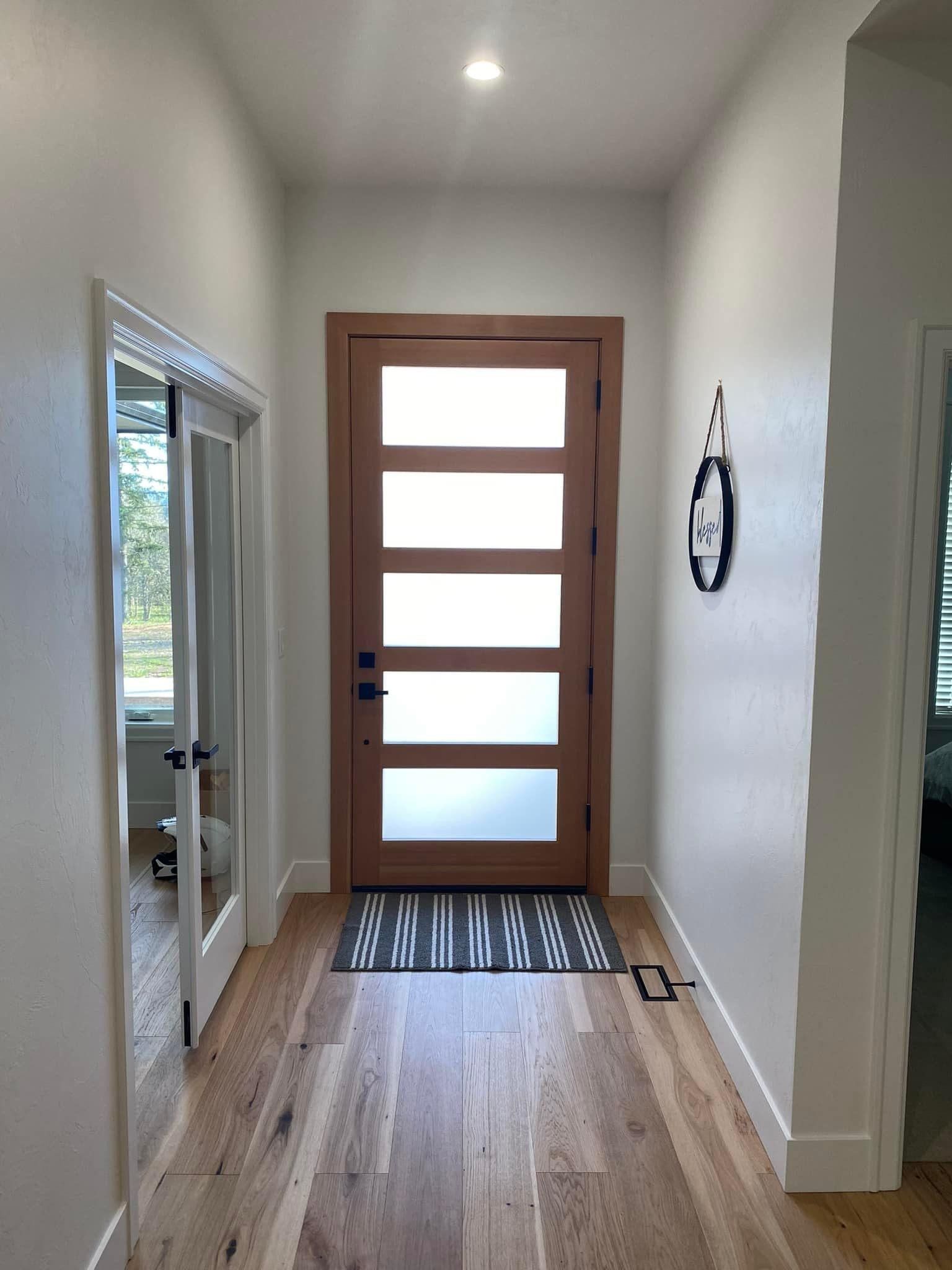 Person painting a living room wall peach, with a ladder, fireplace, and furniture visible.