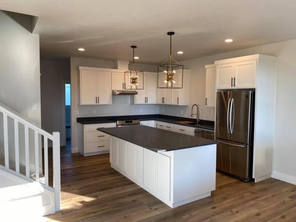 Interior of a room under construction with a kitchen island, scattered materials, and exposed wood flooring.