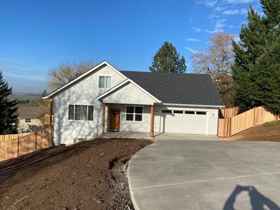 Spacious industrial loft apartment with a leather sofa, arched windows, and a dining table. Warm tones and cityscape visible outside.