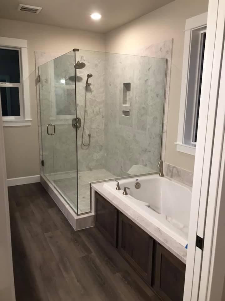 Bathroom under construction: a white floating vanity, bathtub, window, and exposed flooring and walls.