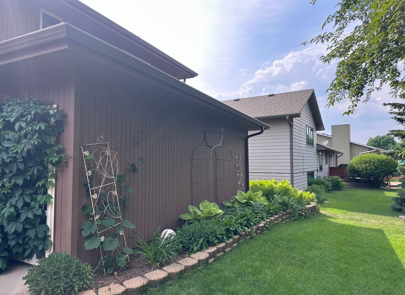A house with a brown fence and a white house in the background.