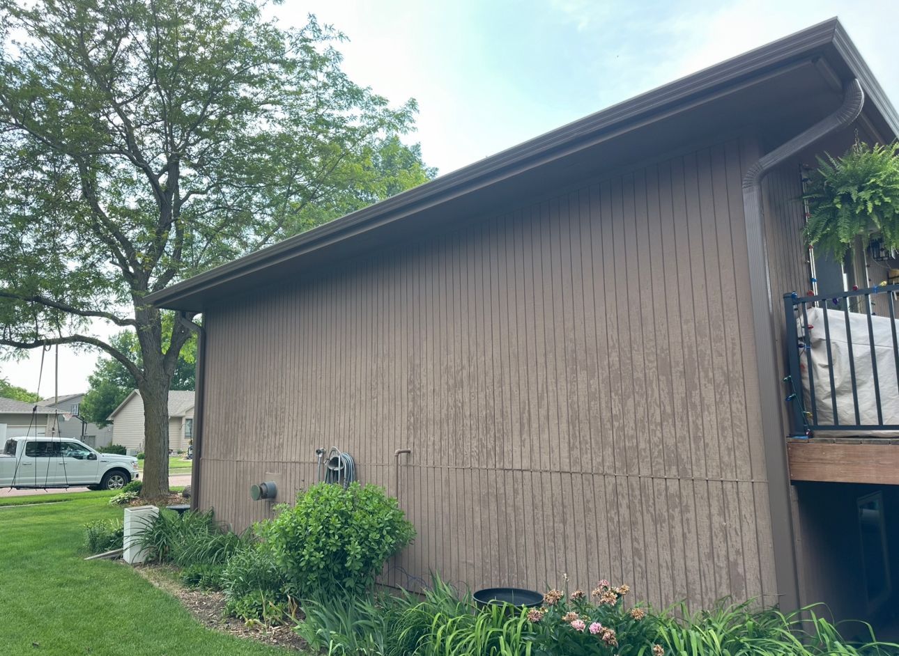 A brown house with a balcony and a white van parked in front of it.