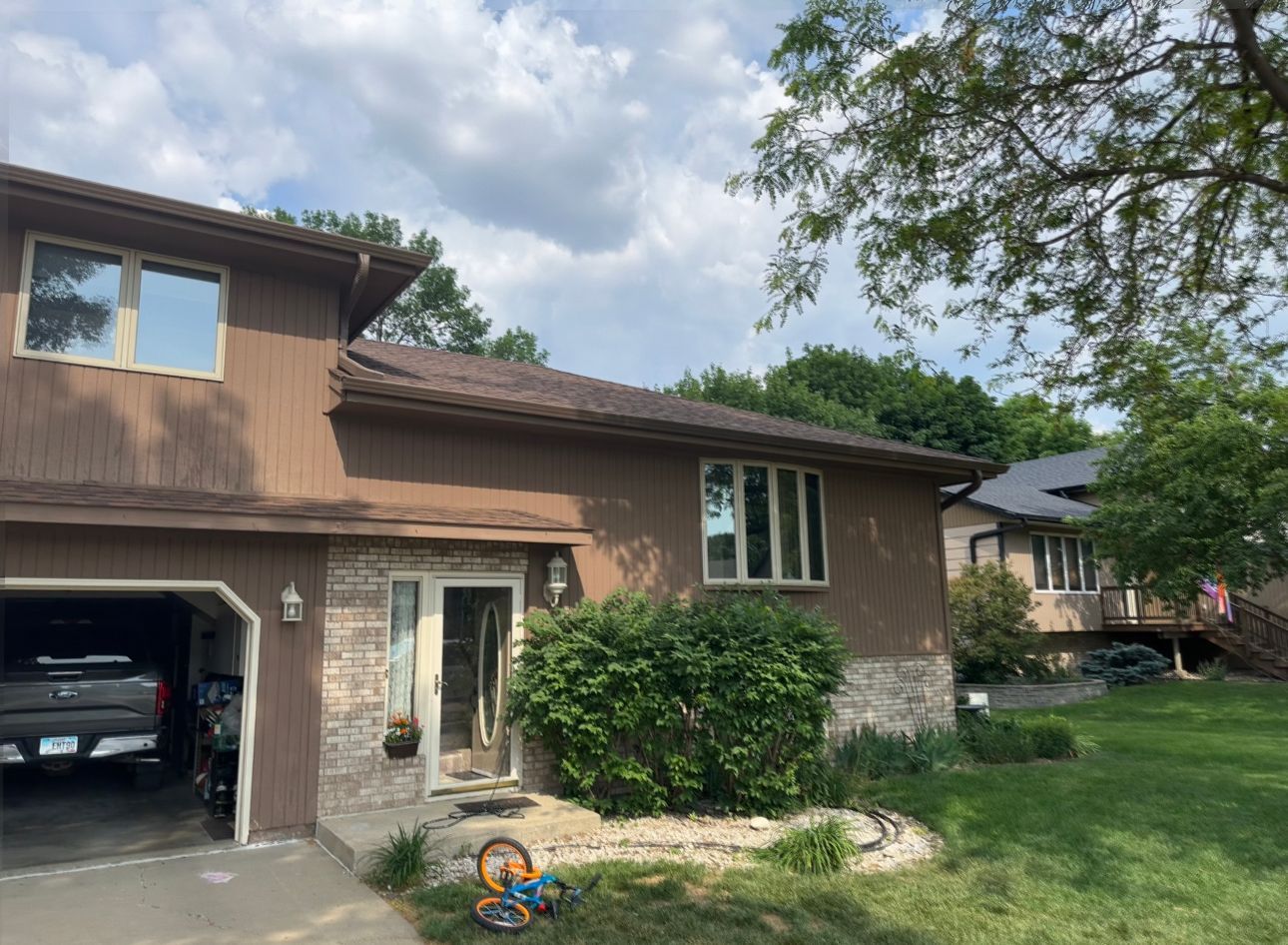 A house with a garage and a bicycle in front of it.