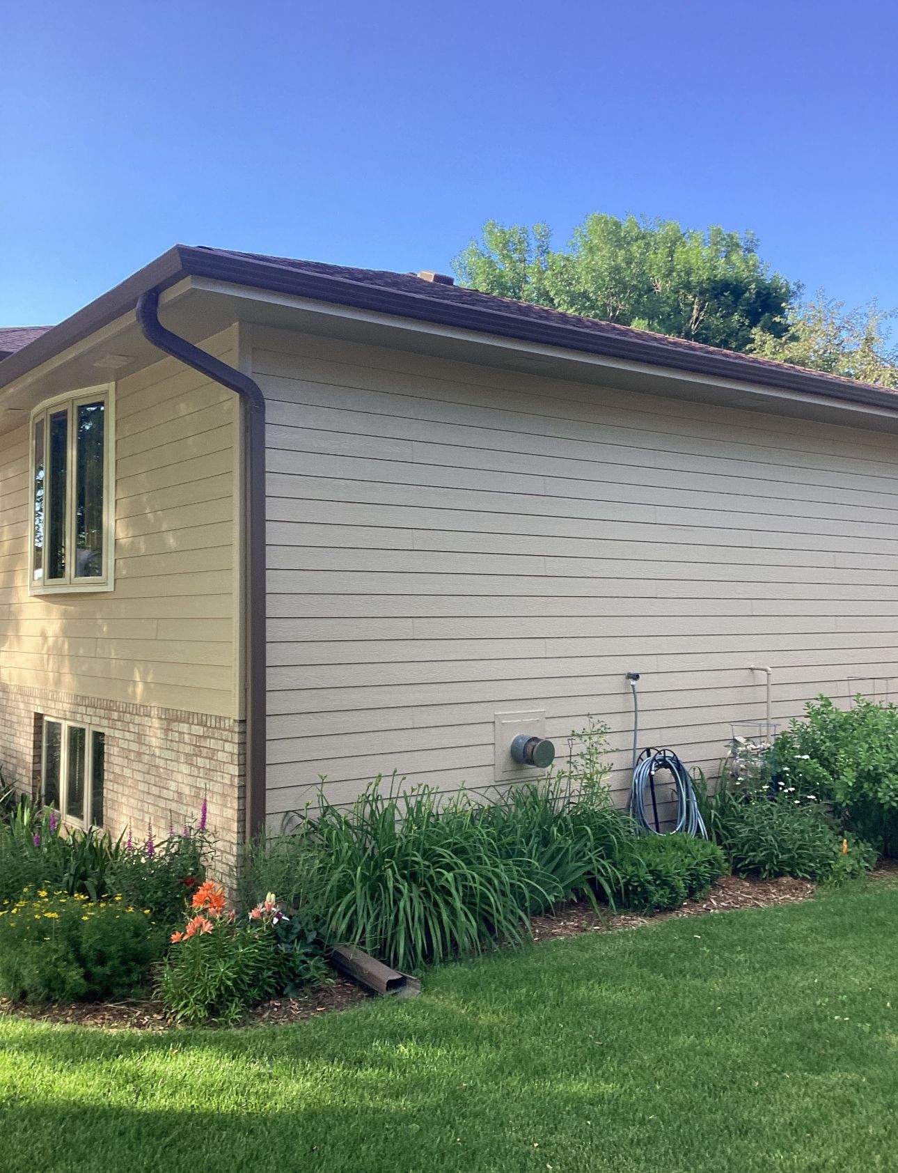 A house with a gutter on the side of it and a lawn in front of it.