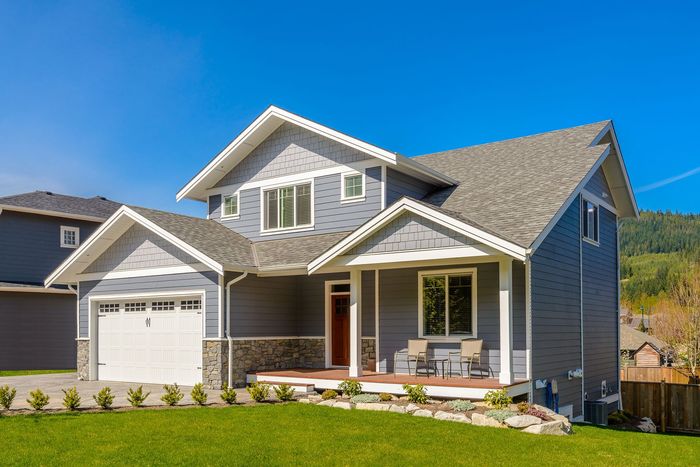 a gray house with a white garage door and a porch .