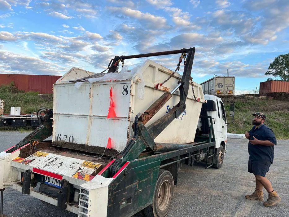 A Green Dumpster Is Sitting In The Grass Next To A Fence — Swift Skips in Gympie, QLD