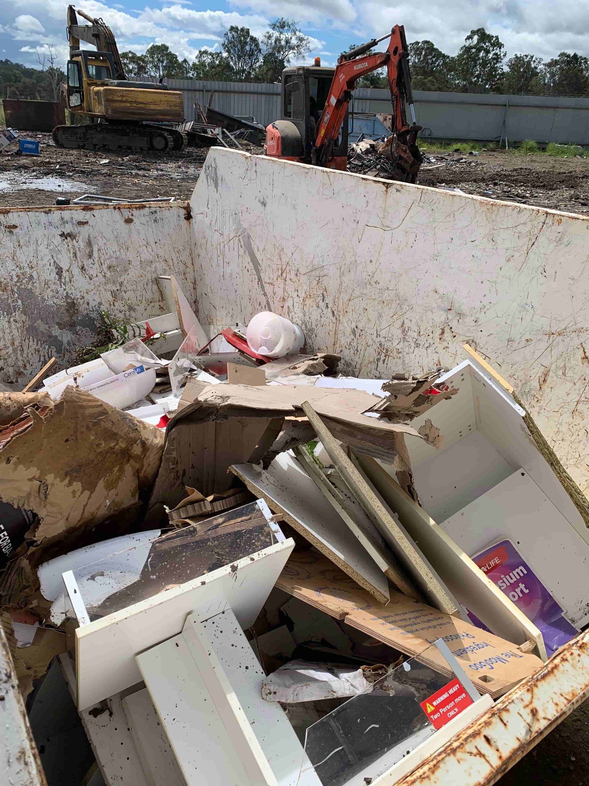 A Dumpster Filled With Trash and a Bulldozer in the Background — Swift Skips in Gympie, QLD