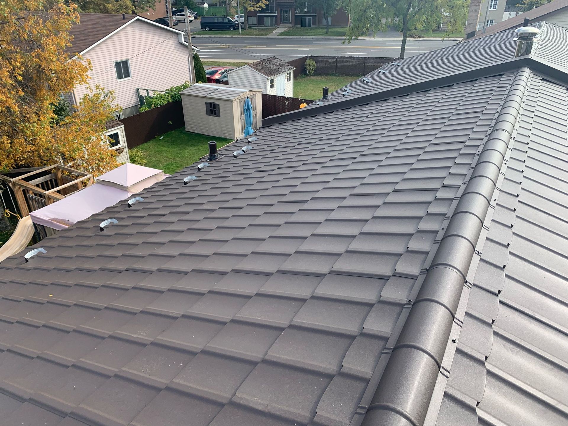 Un toit avec beaucoup de tuiles dessus et une maison en arrière-plan.