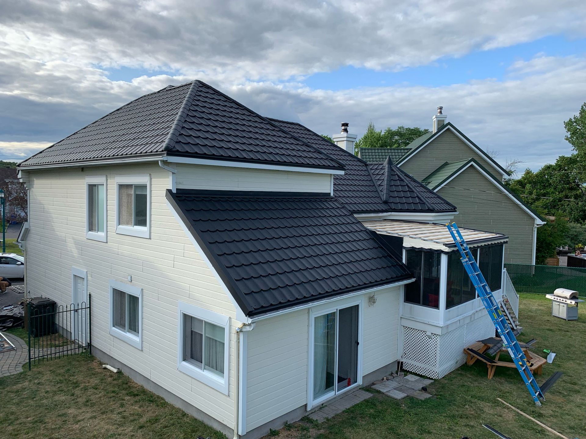 Une maison blanche avec un toit noir est en train d'être peinte.