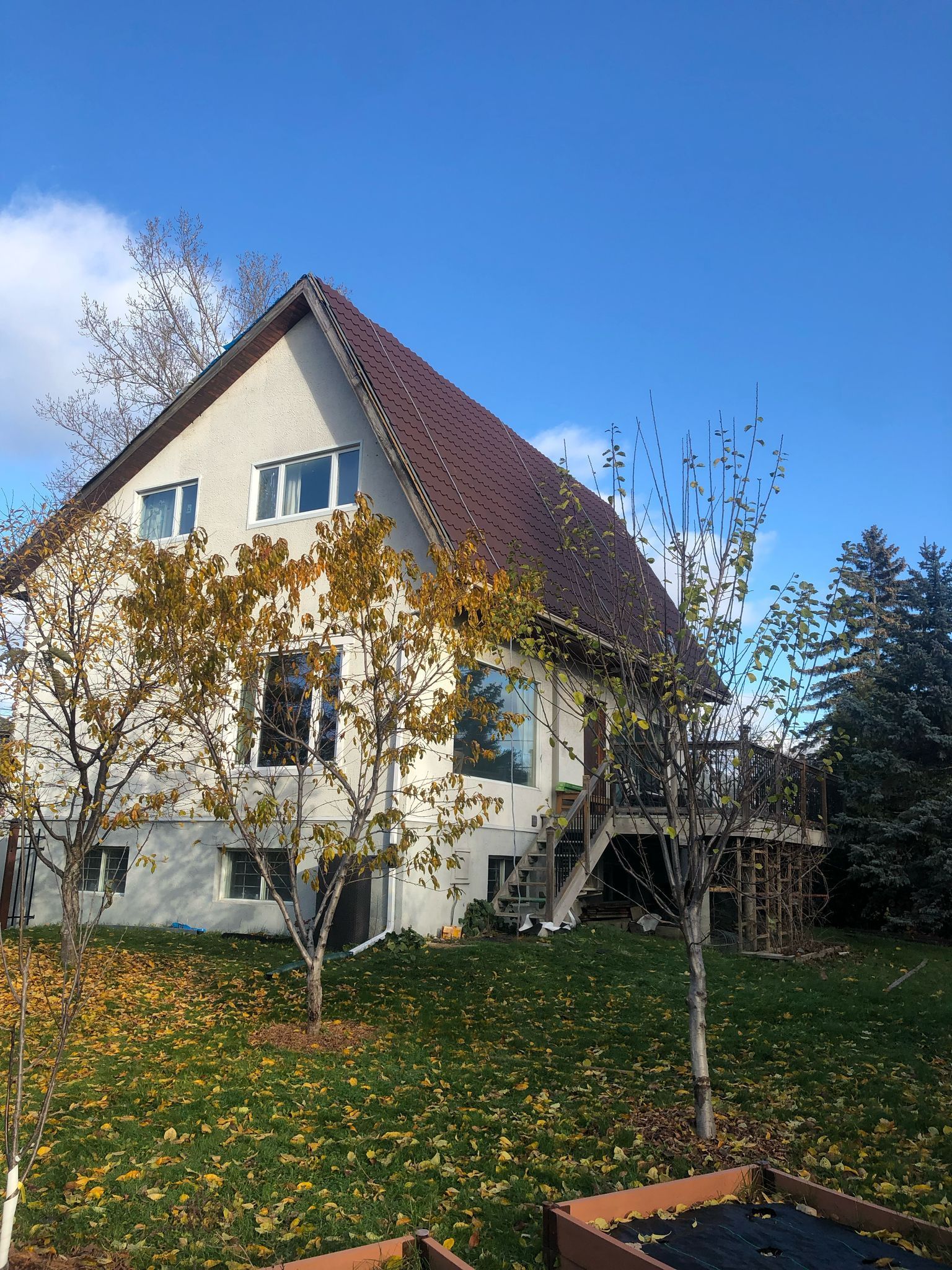 Une grande maison blanche avec un toit rouge est entourée d'arbres.