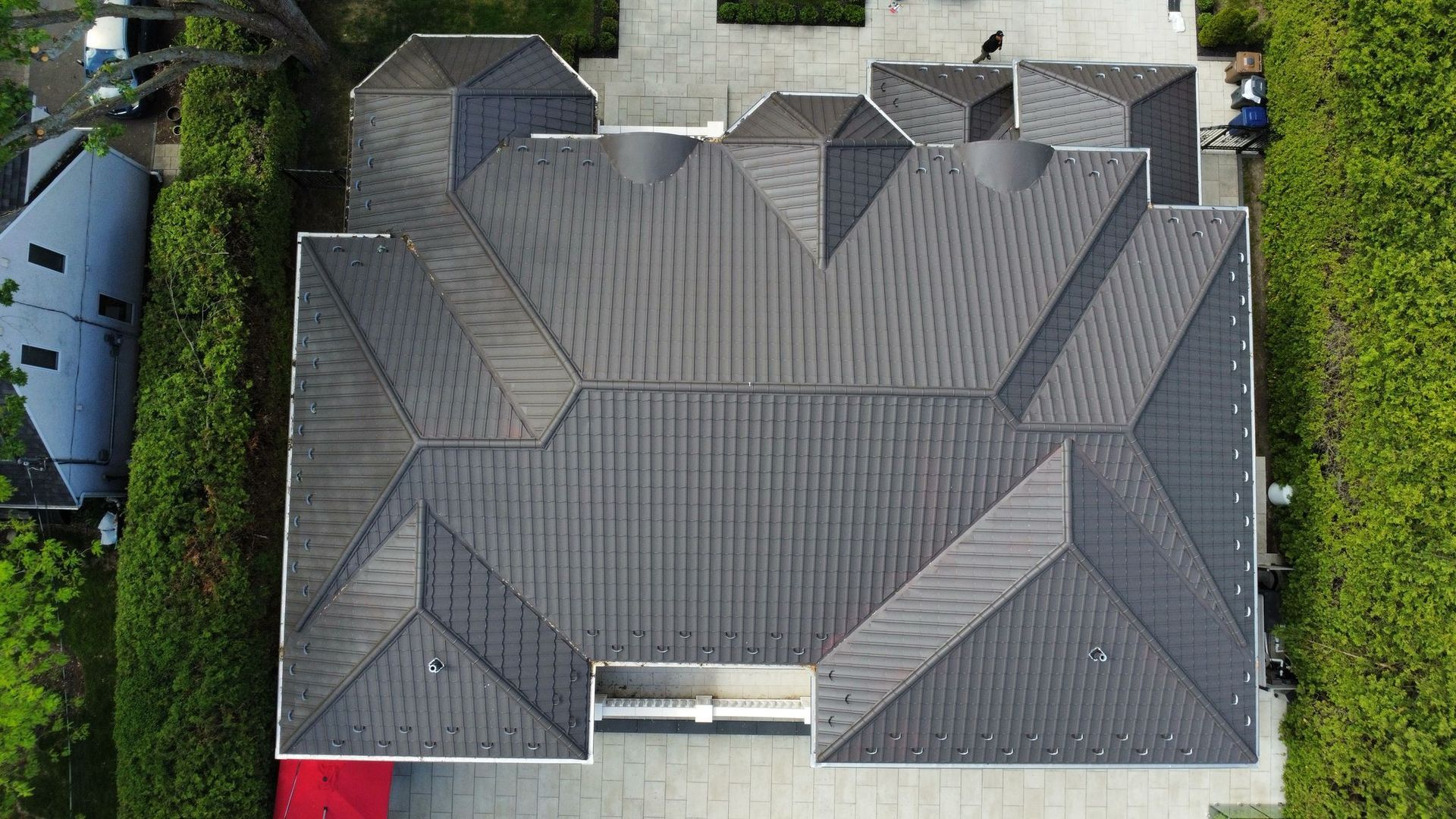 Une vue aérienne d'une grande maison au toit noir entourée d'arbres.