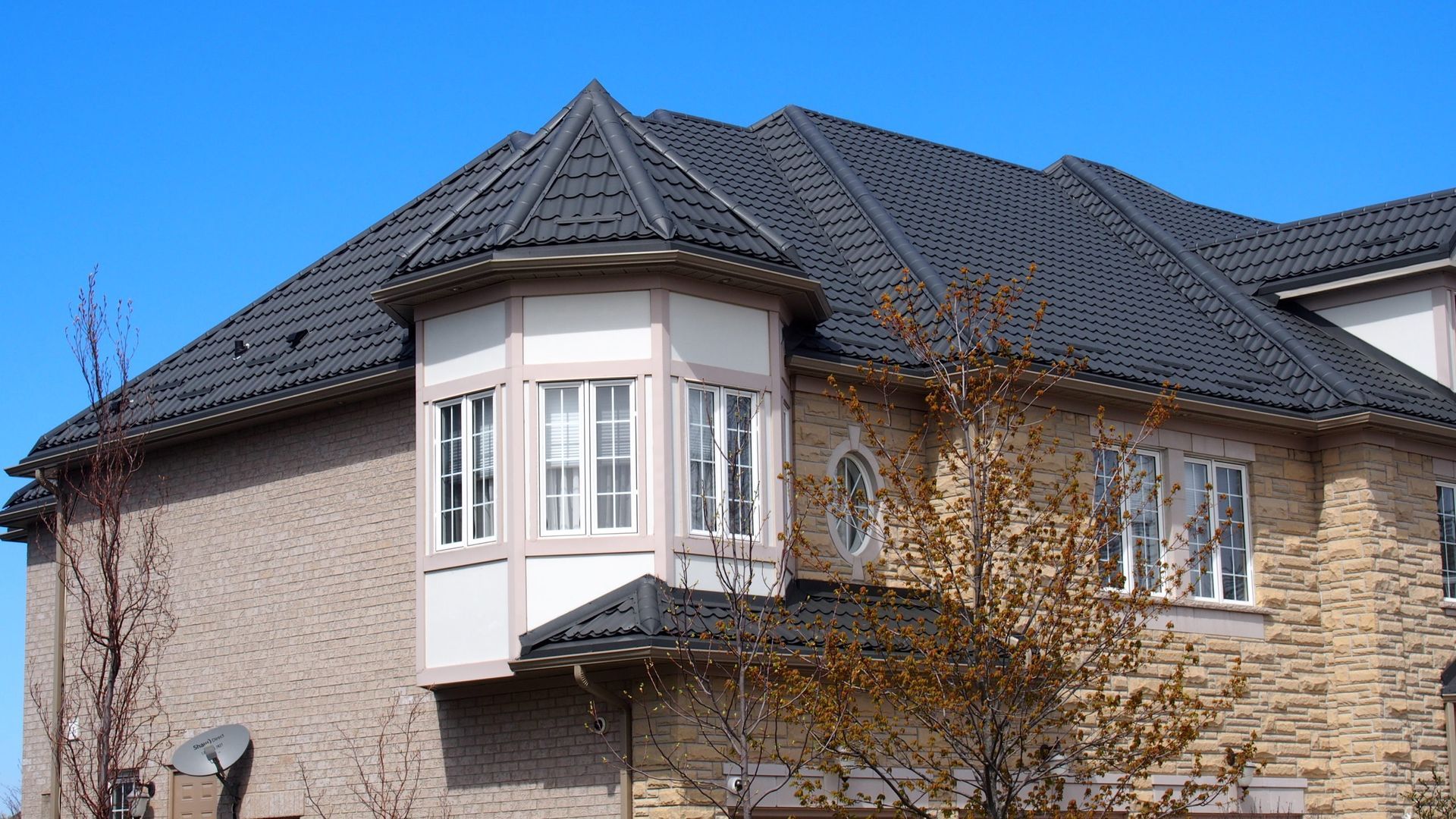 Une grande maison avec un toit noir et une grande baie vitrée