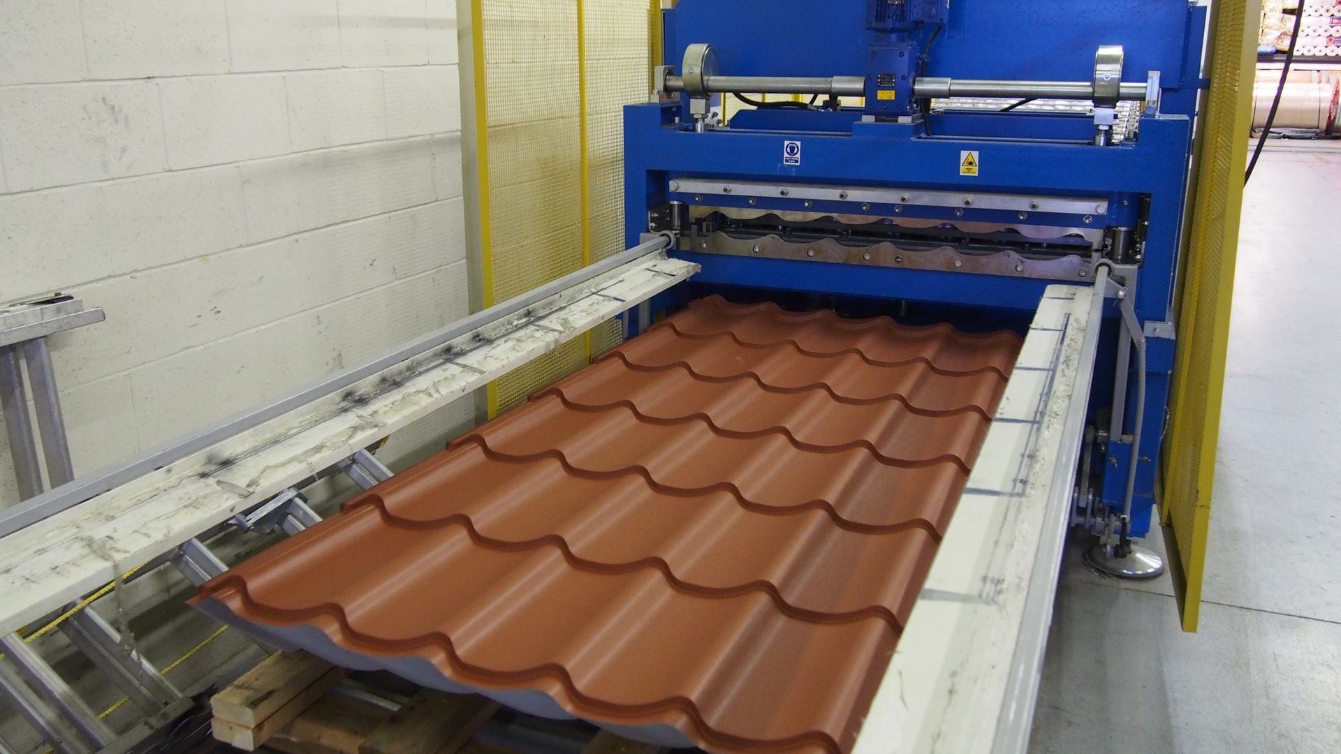 Une machine coupe un toit rouge dans une usine.