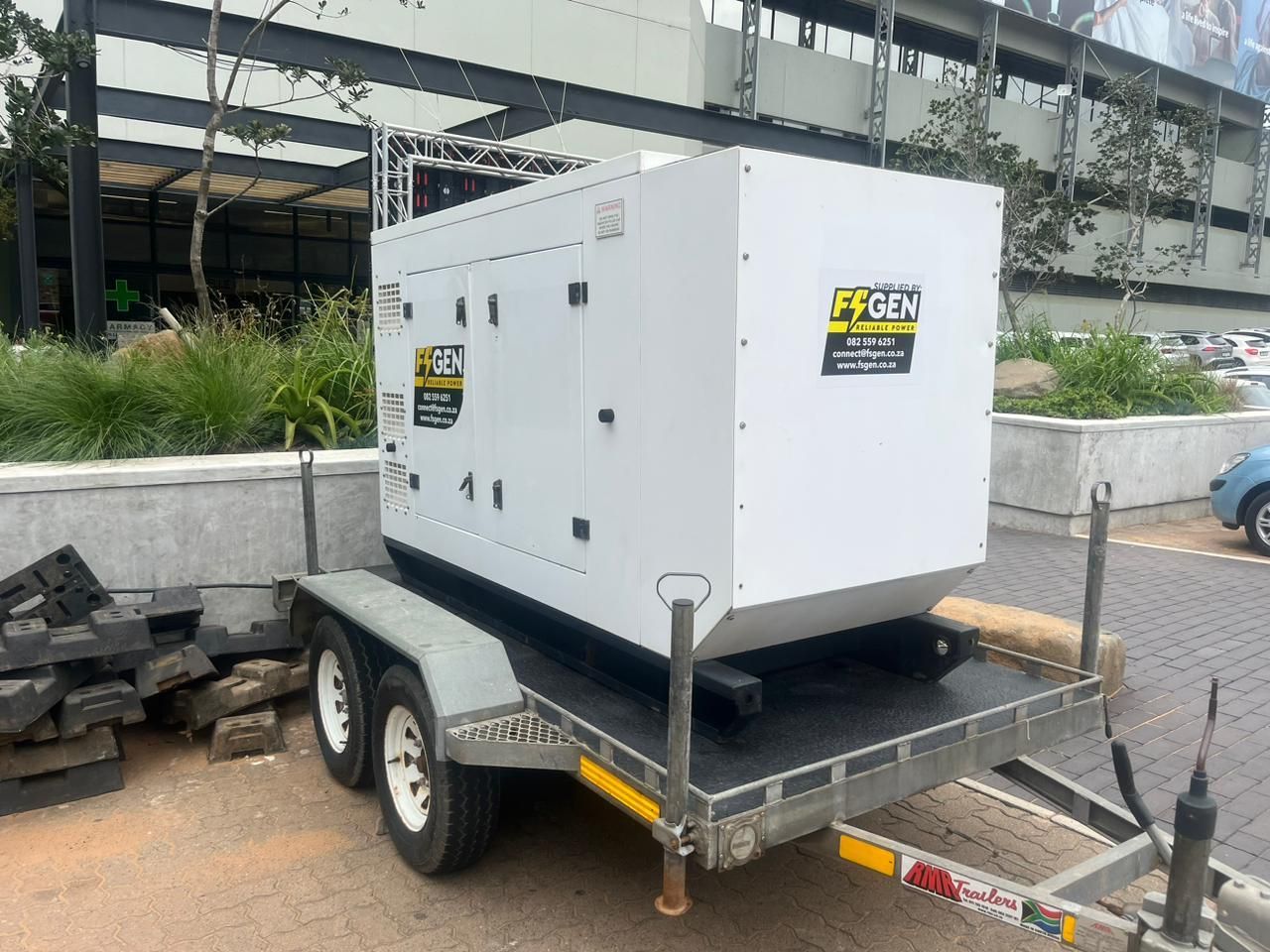 A generator is sitting on a trailer in a parking lot.