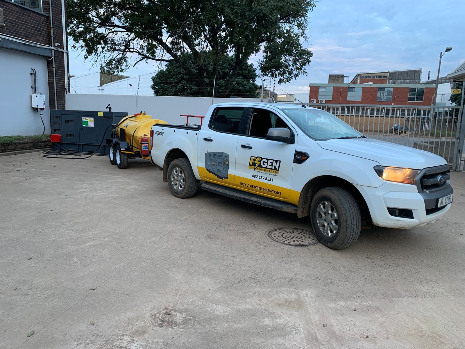 A white truck with a yellow trailer attached to it is parked in a parking lot.