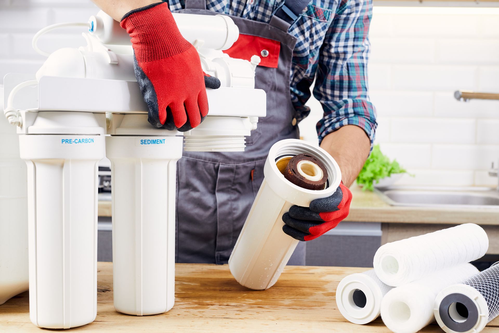 Professional plumber installing a water filter in a home plumbing system.