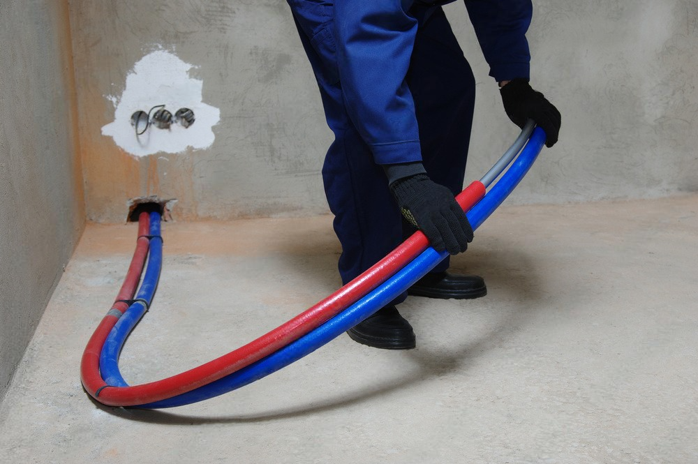 a man wearing a hard hat is working on pipes