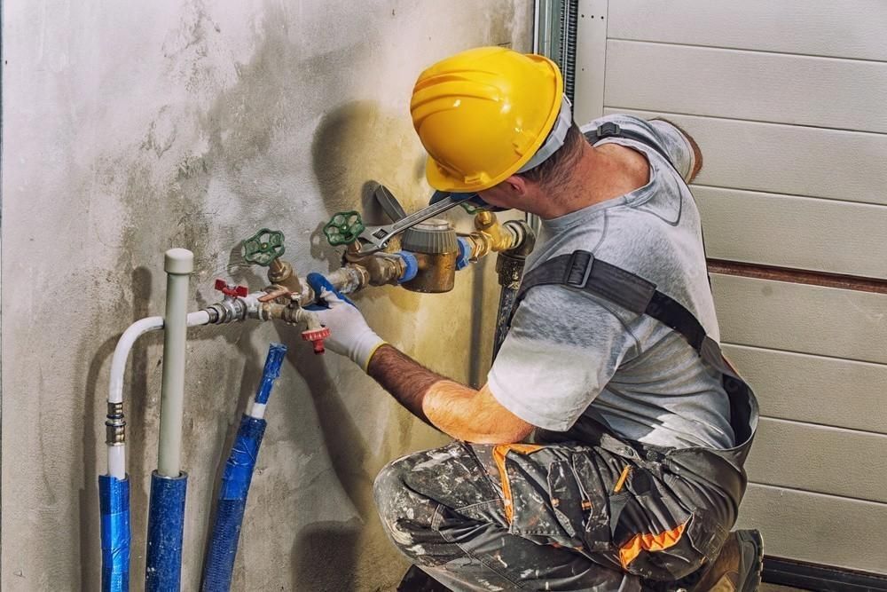 a man wearing a yellow hard hat is working on a pipe