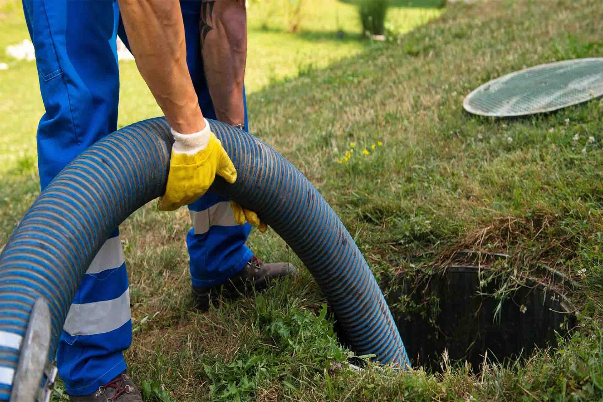 Worker using machinery to empty and clean a household septic tank.