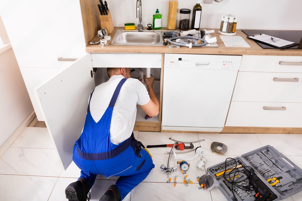 a plumber is working under a sink in a kitchen