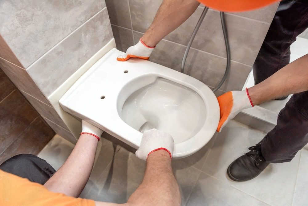 two men are installing a toilet in a bathroom