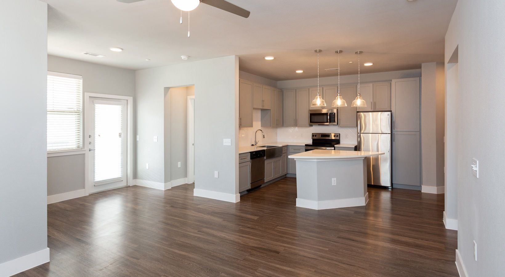 Open-concept kitchen and living area with gray cabinets, island, and stainless appliances.