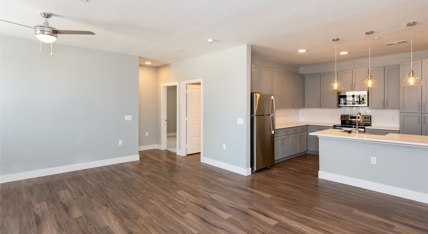 Open-concept living area with gray walls, dark wood flooring, and a modern kitchen with an island.