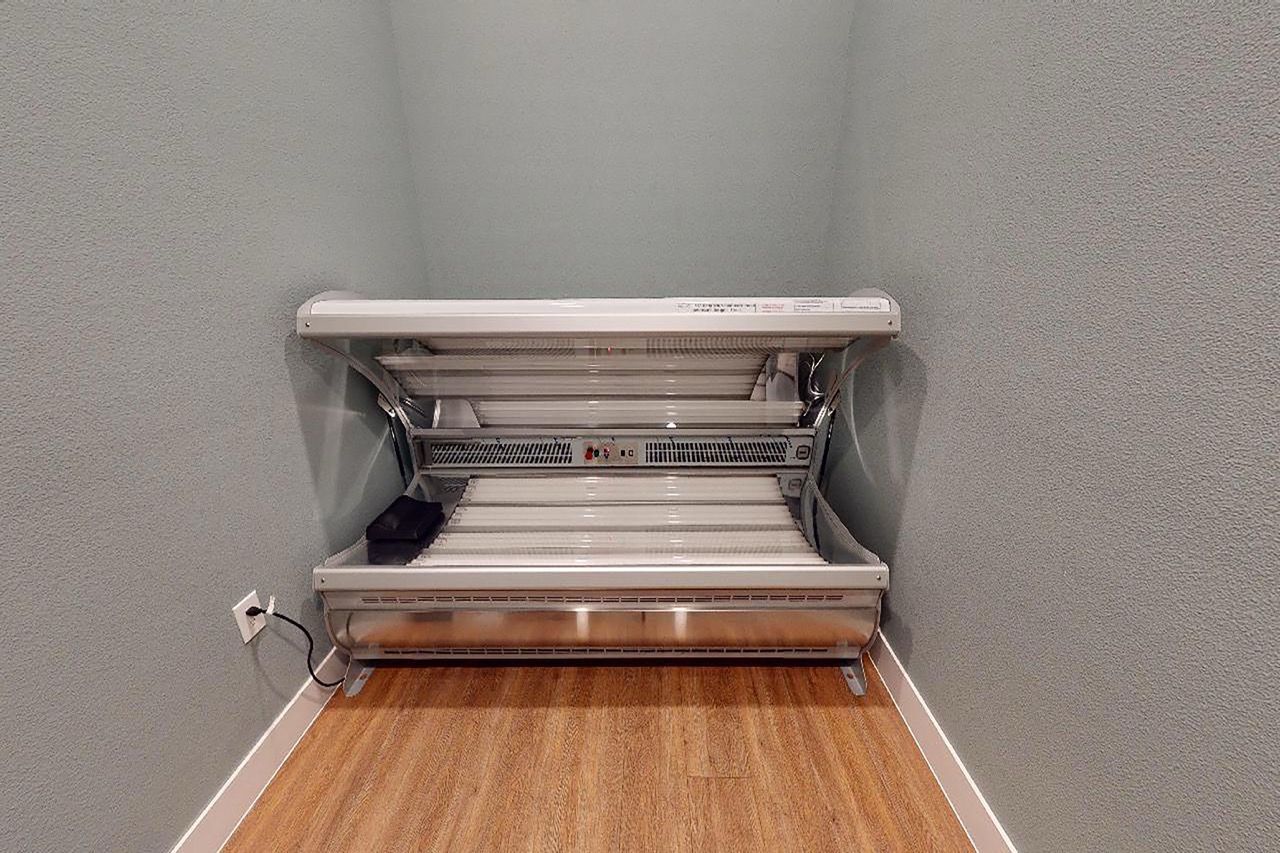 Tanning bed in a small room with blue walls and wood floor.