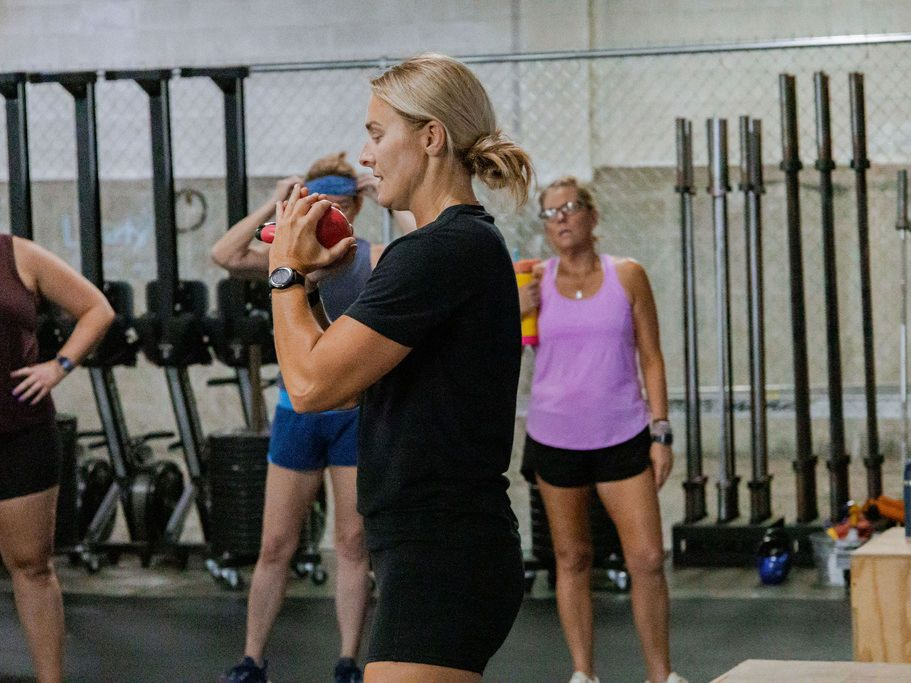 A group of people are sitting on rowing machines in a gym.