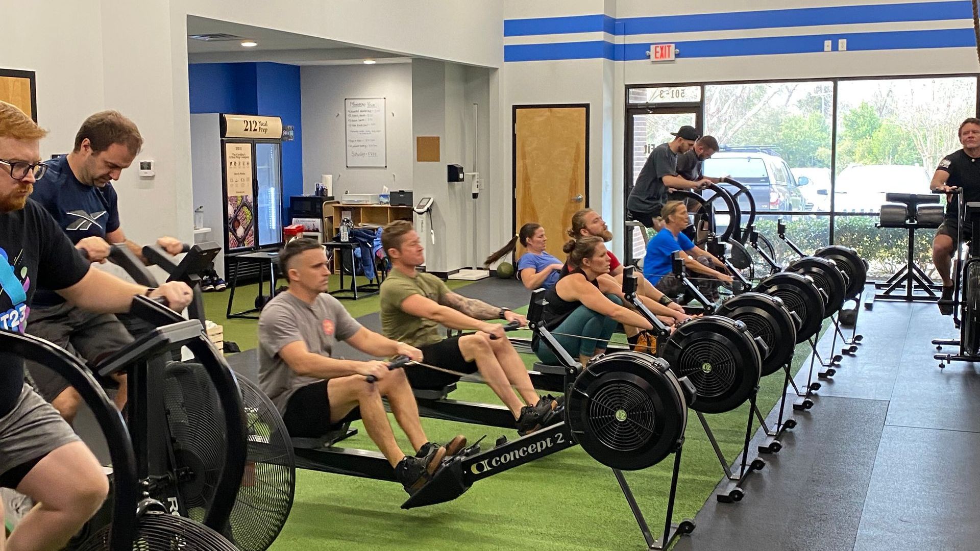 A group of people are rowing exercise bikes in a gym.