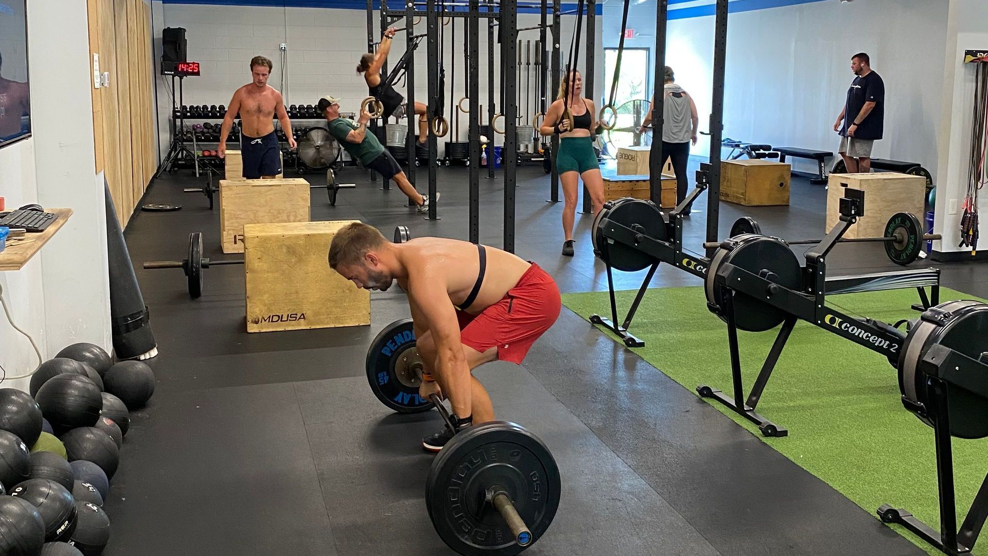 A man is squatting down with a barbell in a gym.