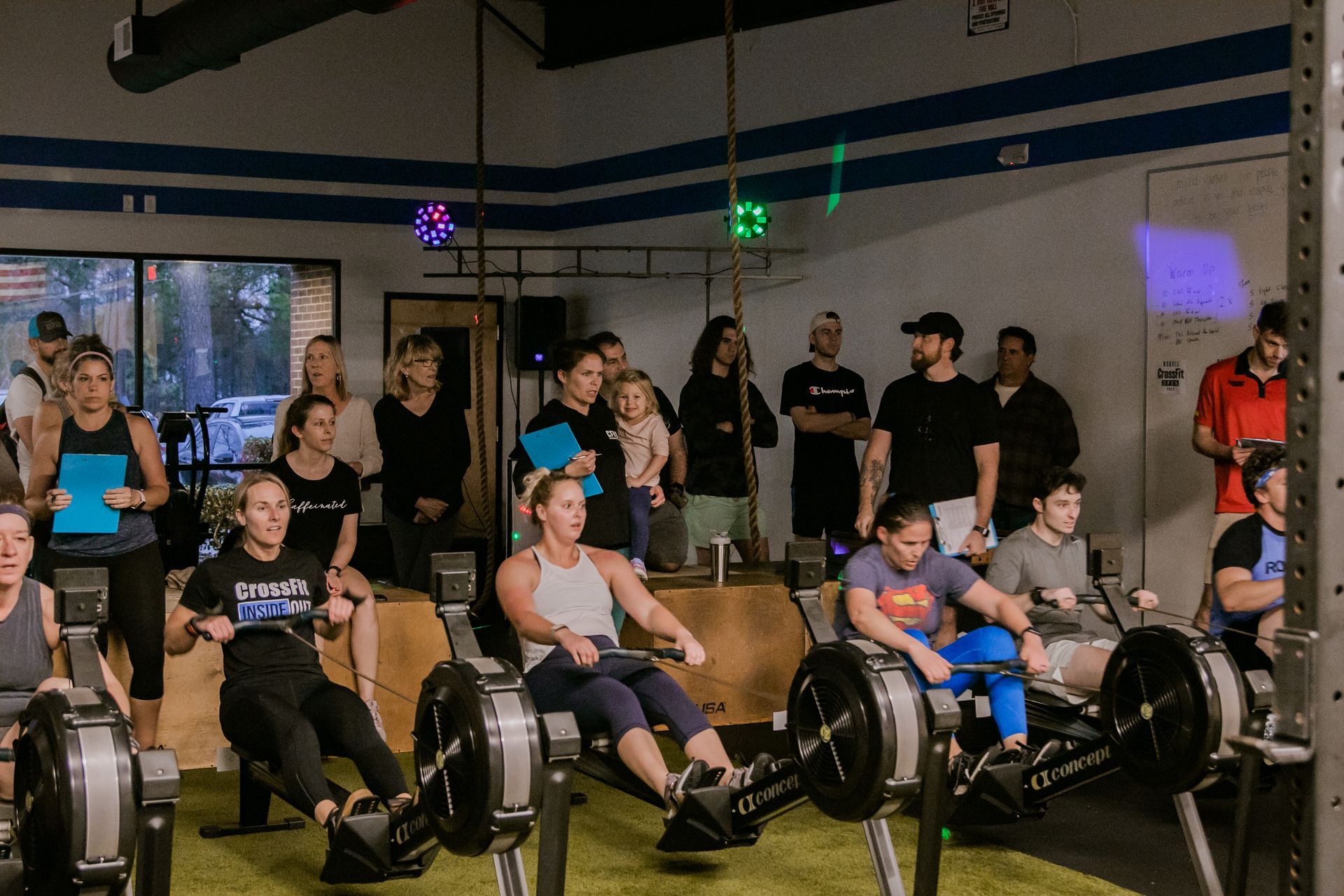 A group of people are sitting on rowing machines in a gym.