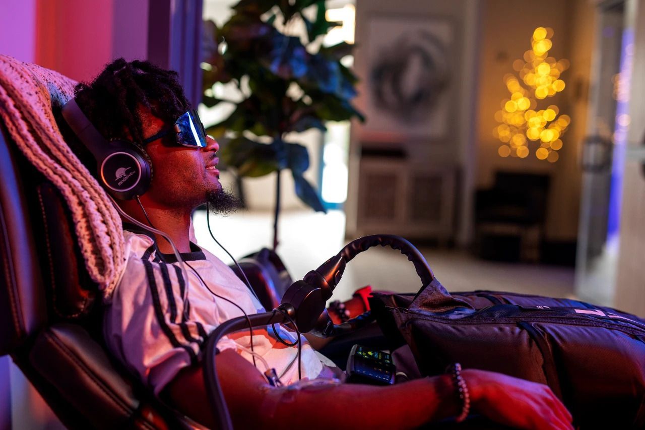 A man is sitting in a chair wearing headphones and sunglasses.