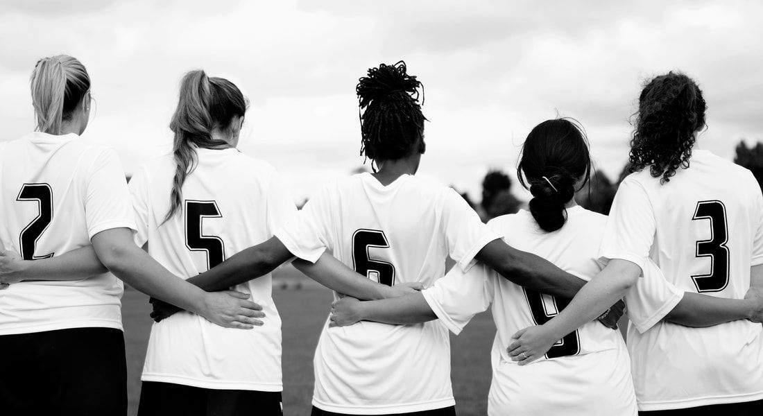 A group of soccer players are standing in a row with their arms around each other.