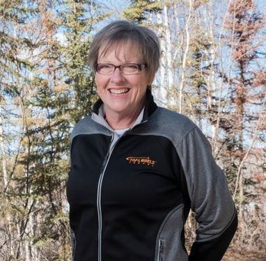 A woman wearing glasses and a black and grey jacket with the word company on it