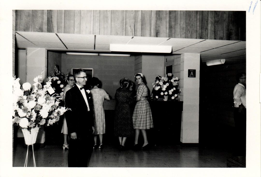 A black and white photo of people standing in a hallway