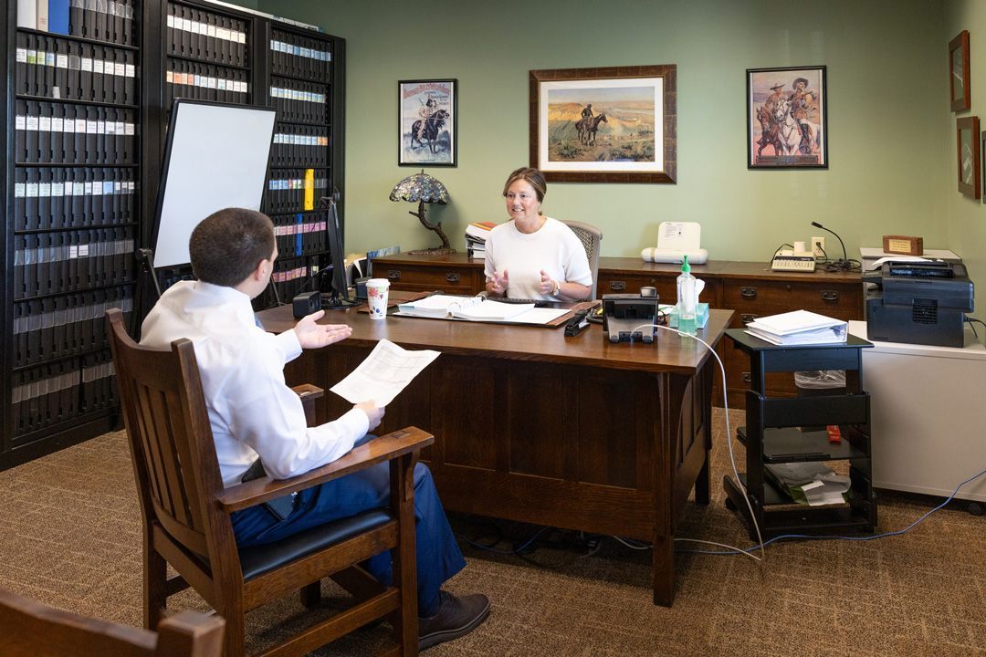 A man and a woman are sitting at a desk in an office.