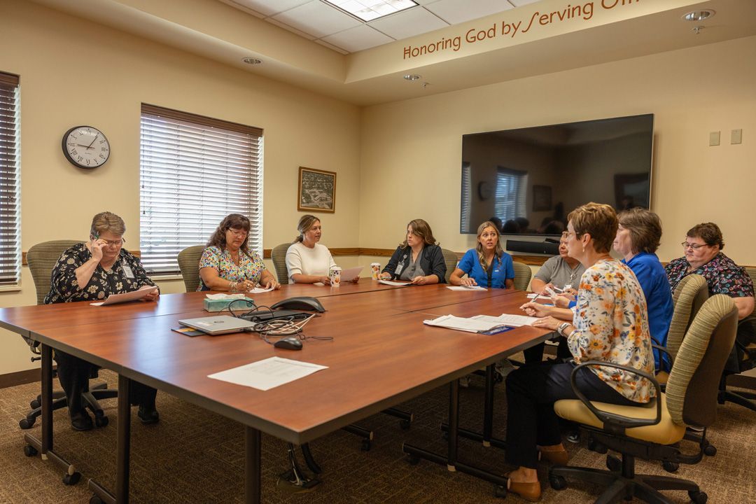 A group of people are sitting around a long table in a conference room.