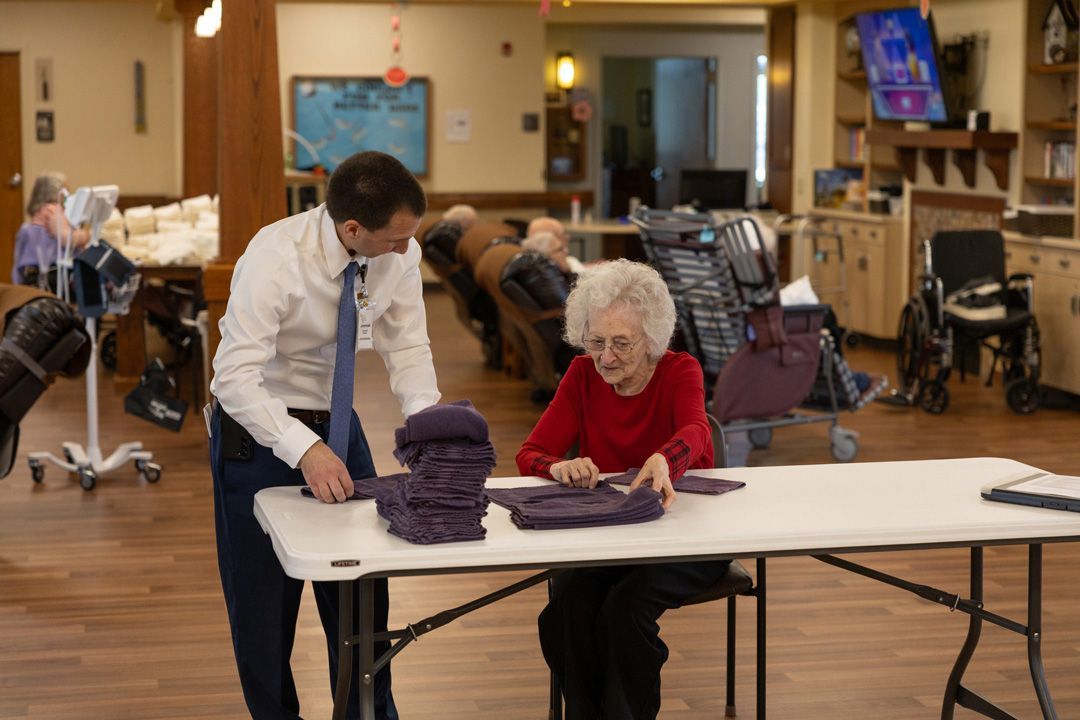 A man and a woman are sitting at a table in a nursing home.