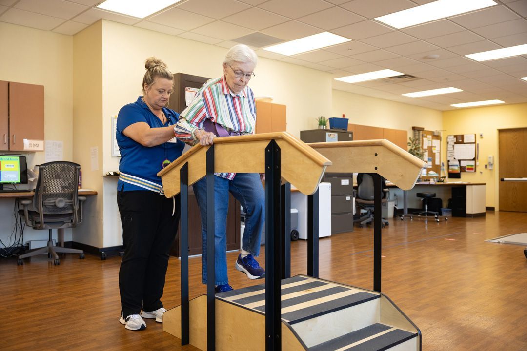 A woman is helping an elderly man walk up stairs.