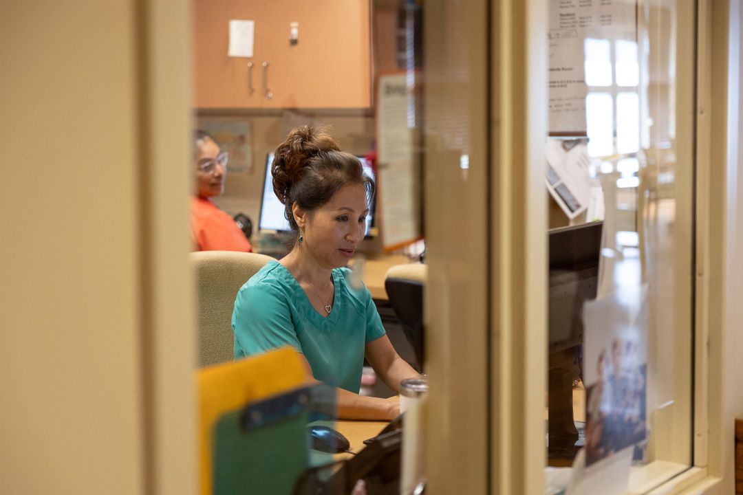 A woman is sitting at a desk in front of a computer.