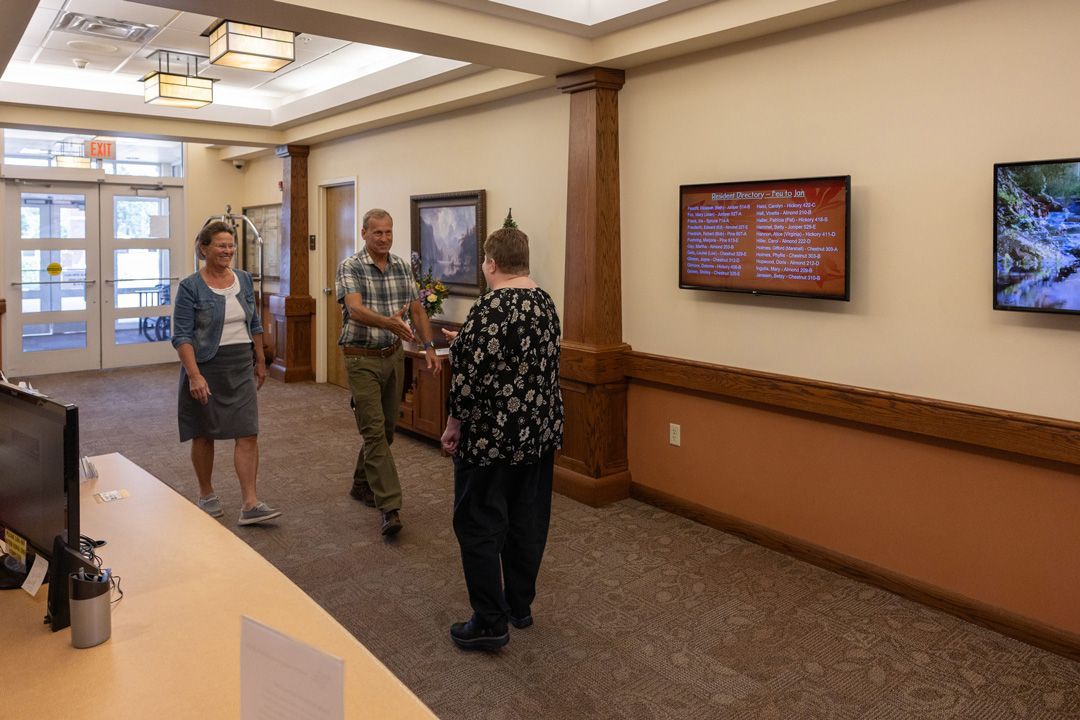 A group of people are standing in a hallway talking to each other.