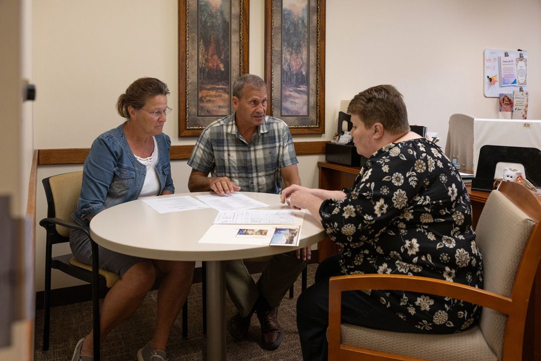A group of people are sitting around a table talking to each other.