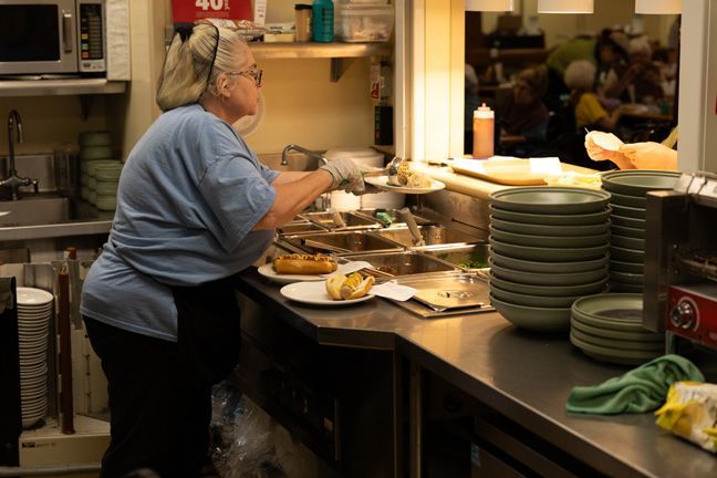 A woman is standing in a kitchen preparing food.